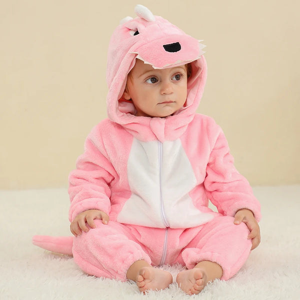 Bilden visar en gullig och mjuk rosa T-Rex dinosauriedräkt för barn. Dräkten är gjord av lurvigt flanellmaterial med mörkare rosa fläckar, en vit mage och en rad taggar ner längs ryggen och svansen. Huvan är utformad som ett sött dinosauriehuvud med stora ögon och små tänder, vilket gör den perfekt för lek och utklädnad.