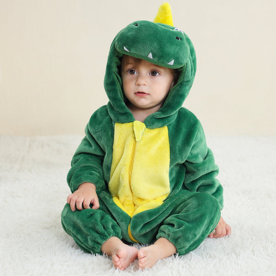 Bilden visar en cool och detaljerad grön T-Rex maskeraddräkt för barn, sett från sidan för att framhäva den långa, stoppade svansen. Dräkten är gjord av mjukt textil med ett realistiskt reptilmönster och har en fastsatt huva med ett dinosauriehuvud, som fullbordar det vilda utseendet för lek eller maskerad.