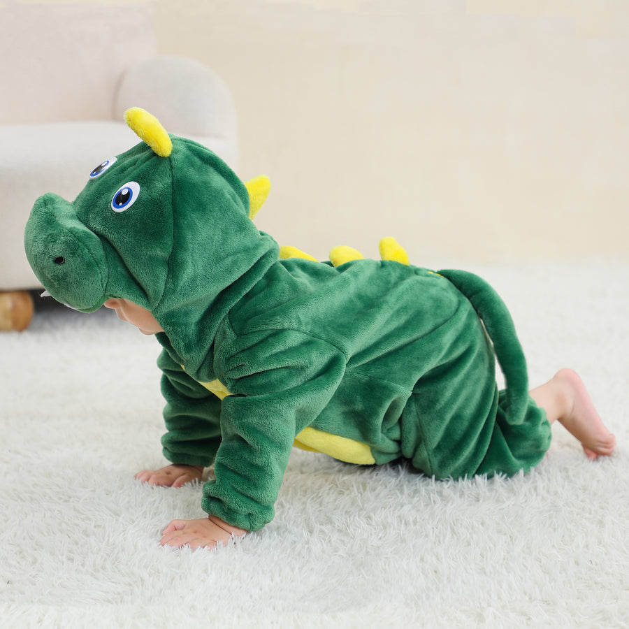 En charmig, grön T-Rex maskeraddräkt för barn gjord av mjukt flanellmaterial. Dräkten har en vit mage, en rad orange taggar ner längs ryggen och en lång svans. Huvan är formad som ett dinosauriehuvud med stora ögon och vita tänder, vilket gör den perfekt för både lek och maskerad.