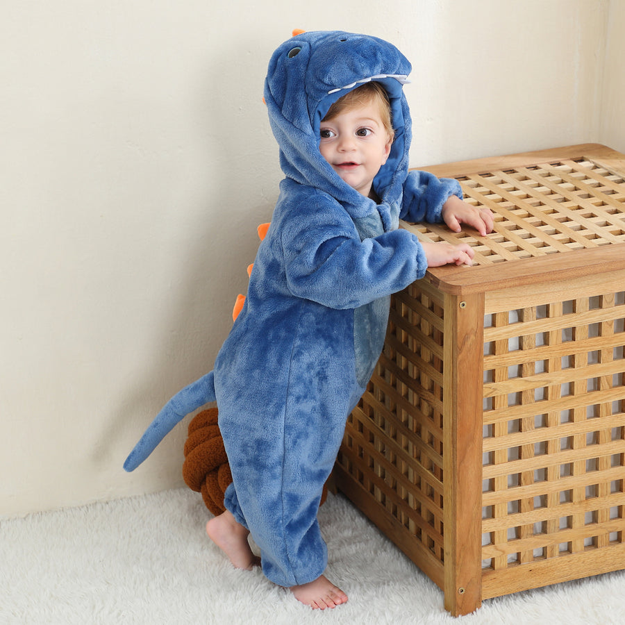 En gullig och mjuk blå T-Rex maskeraddräkt för barn, formad som en heldräkt i lurvig flanell. Dräkten har en vit mage, roliga taggar längs ryggen och en matchande huva med ett vänligt dinosaurieansikte, som är perfekt för lek och utklädnad.