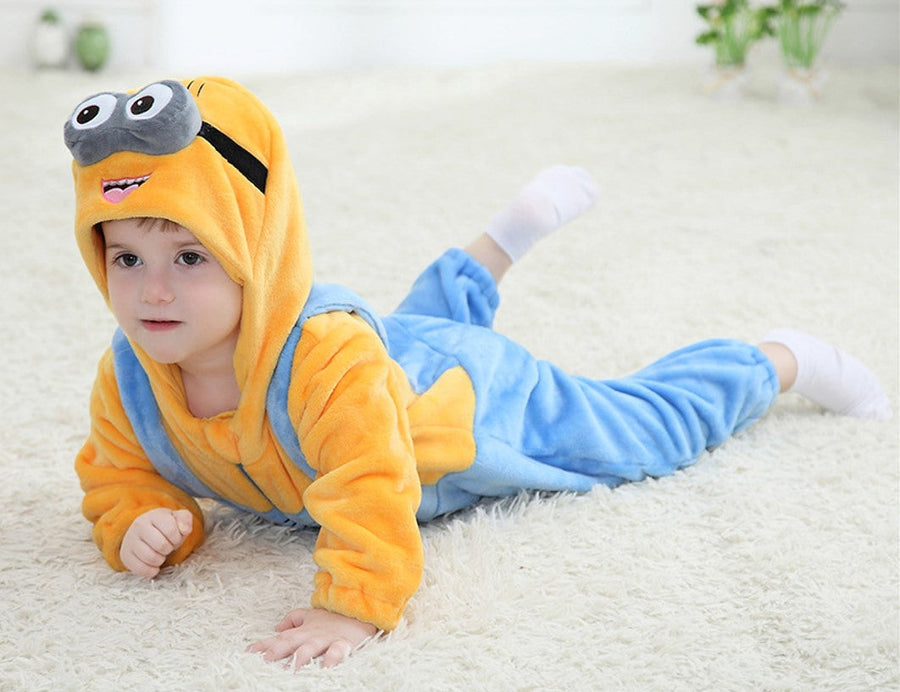 En härlig Minion-maskeraddräkt för barn, som består av en gul överdel och klassiska blå hängselbyxor med ficka. Dräkten inkluderar en integrerad gul huva med karakteristiska glasögon och små hår på toppen, vilket fullbordar det roliga och igenkännbara utseende från filmerna. Materialet ser mjukt och bekvämt ut, perfekt för lek och maskerad.
