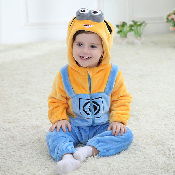 En färgglad Minion-maskeraddräkt för barn gjord av mjukt, gult och blått flanell. Dräkten har de klassiska denim-hängselbyxor detaljer, en huva med ett stort öga och glasögon samt små hår på toppen, vilket gör den perfekt för lek och maskerad.